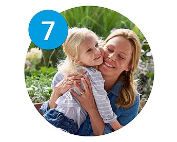 A woman and a young girl are hugging outdoors.