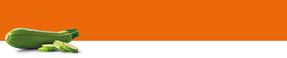 A green zucchini with a few slices is presented against a white and orange background.