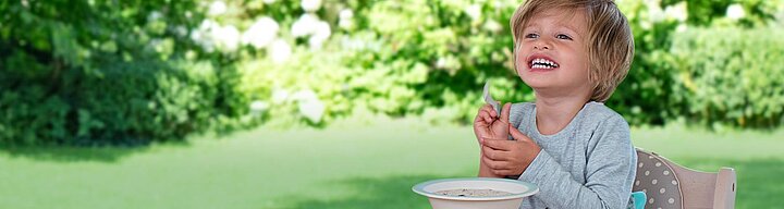 A child is eating from a bowl outdoors.