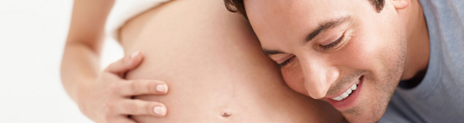 A man is embracing a pregnant woman.