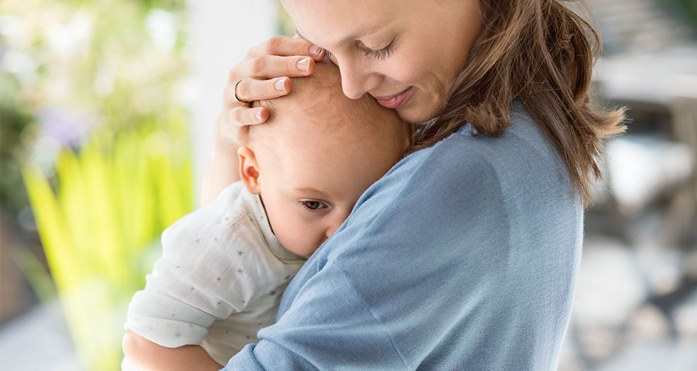 A woman lovingly holds a baby.